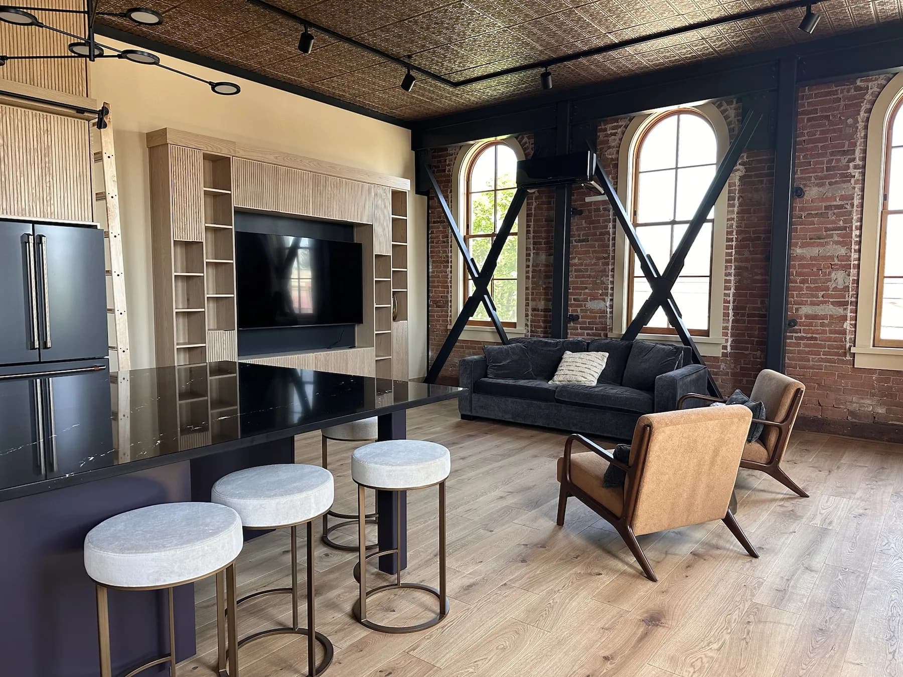 Living area with historic arched windows, exposed brick, and lounge seating